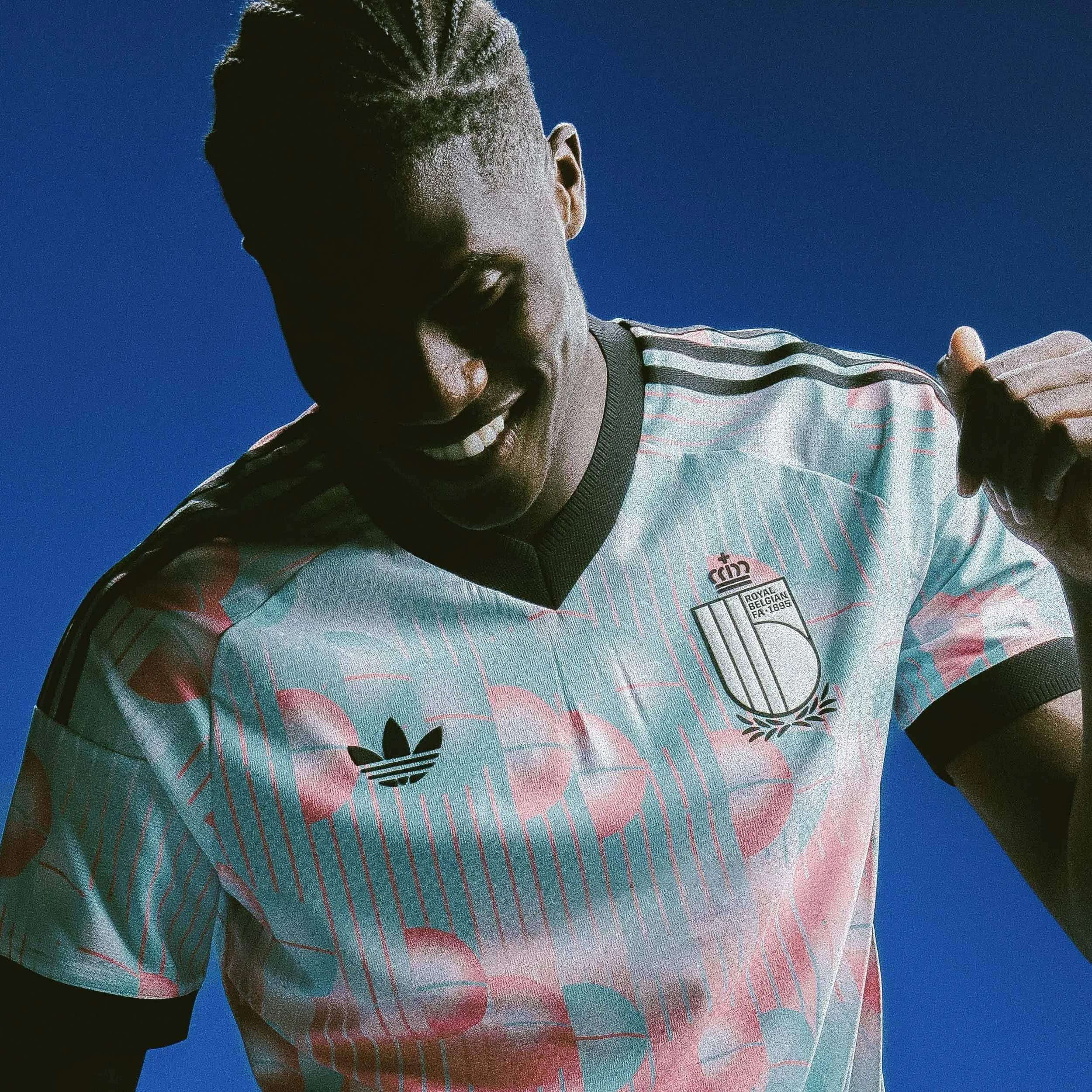 jersey_image | UAE SPORT STORE Person wearing a pastel-striped polo shirt with a crest on the chest, photographed from below against a bright blue sky, as if mid-action.