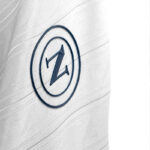 kb | UAE SPORT STORE Close-up of a circular navy logo with a stylized Z on white fabric