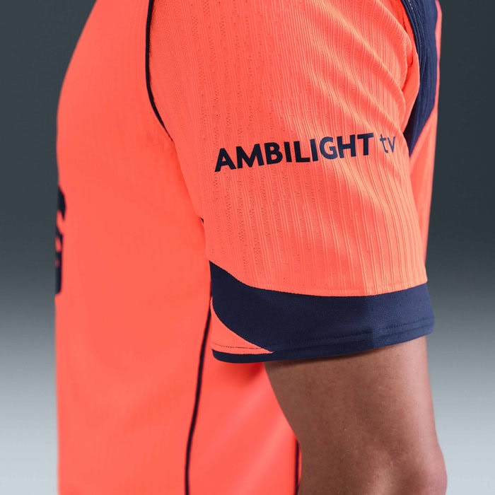 kd | UAE SPORT STORE Close-up of a bright orange sports jersey sleeve with navy trim and the text 'AMBILIGHT TV' on the upper arm.