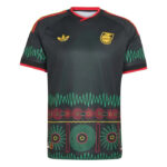Black soccer jersey with red trim and a gold logo on the left chest, a crest on the right chest, and teal zigzag bands with circular motifs across the bottom of the shirt.