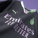 Close-up of a dark soccer jersey with light purple Emirates Fly Better slogan, mint-green Puma logo, and AC Milan crest visible on the chest cutout area.