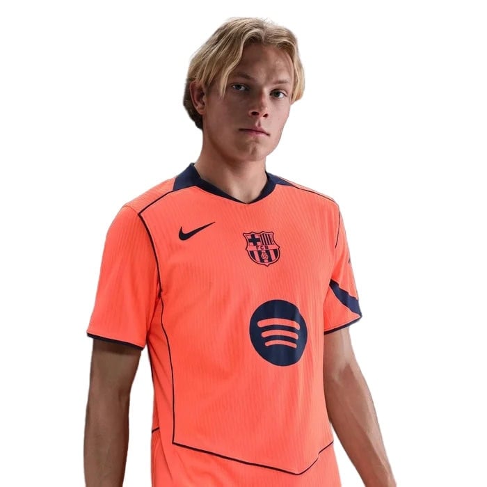 ku | UAE SPORT STORE Young man wearing a neon orange FC Barcelona football jersey with the Spotify sponsor logo on the chest and a Nike swoosh nearby