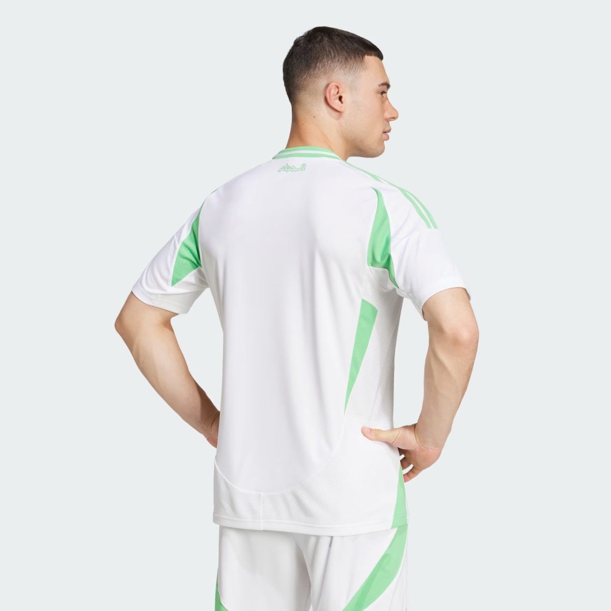 Model wearing white athletic kit with mint green accents, shown from the back with hands on hips