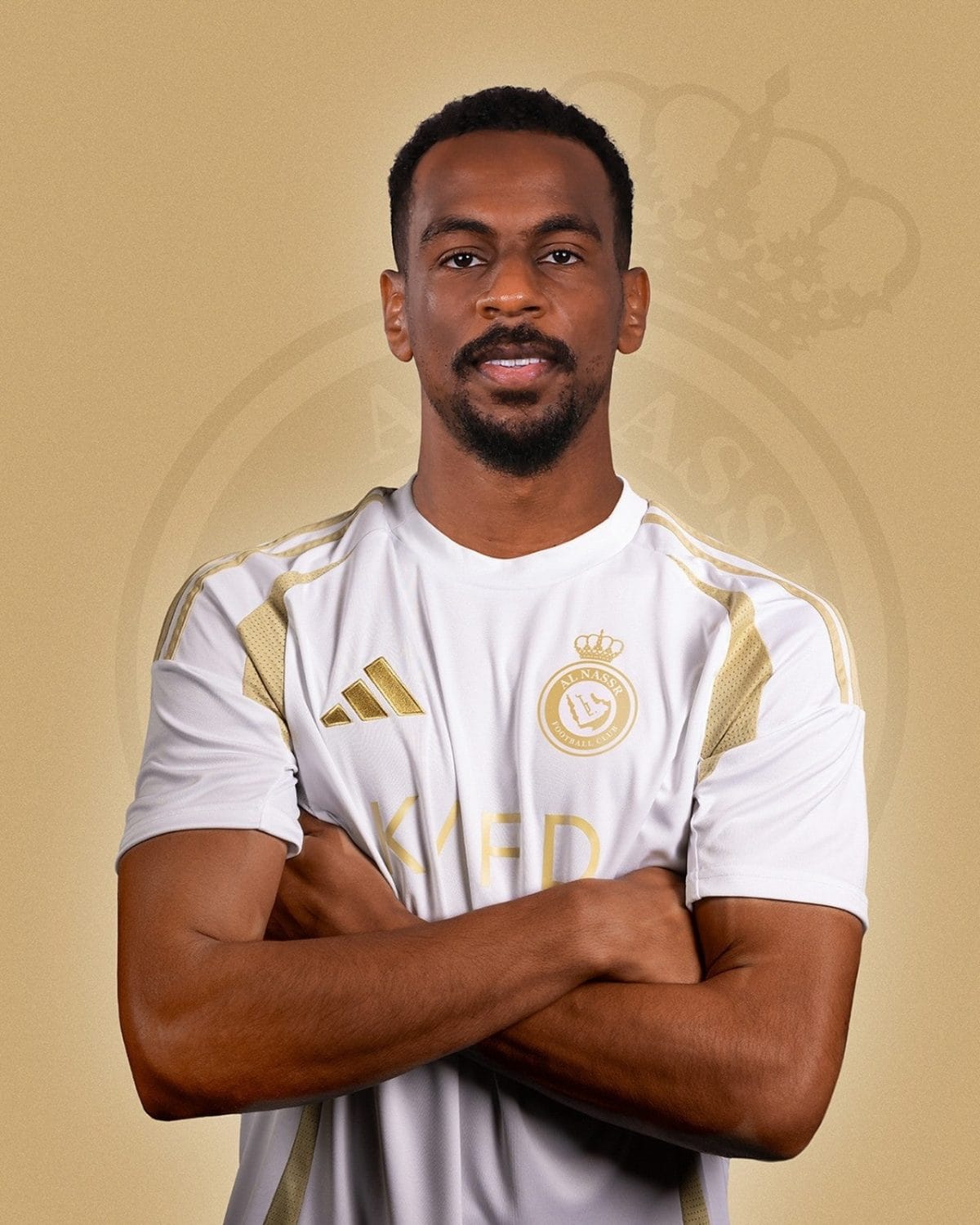 Portrait of a man with arms crossed, wearing a white and gold sports jersey with a crest visible on the chest.