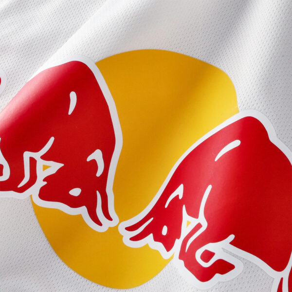 Close-up of the Red Bull logo on white fabric, showing a yellow circle behind two red charging bulls.
