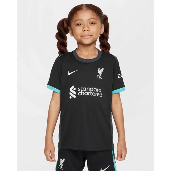 Young girl in a black Liverpool FC training jersey with teal trim, standing and smiling.