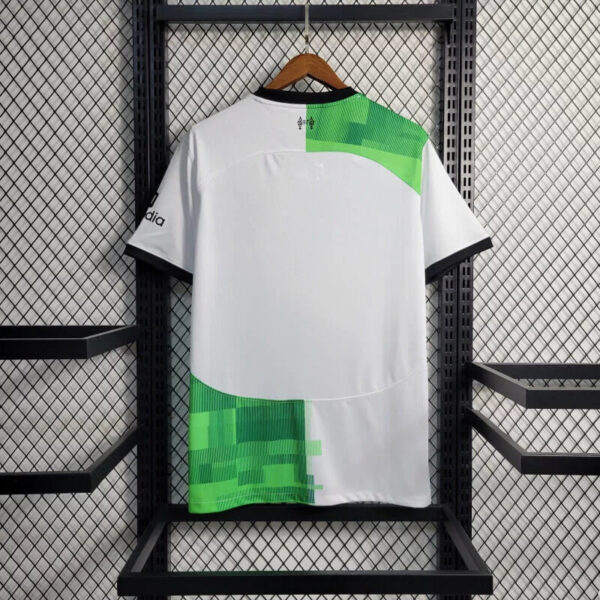 Back view of a white athletic jersey with neon green geometric panels on the shoulder and lower back, hanging on a wooden hanger against a mesh backdrop.