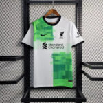 Liverpool FC football jersey on a hanger with white and bright green geometric blocks and sponsor logo 'standard chartered' on the front, Nike swoosh visible.