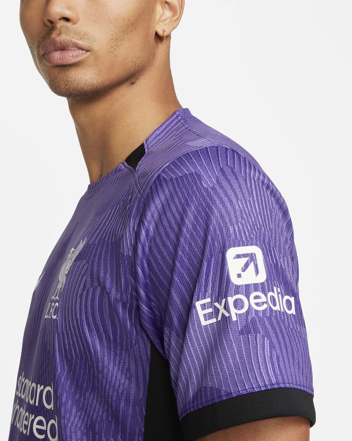 Close-up of a person’s shoulder and neck wearing a purple striped athletic jersey, with a white logo on the sleeve.