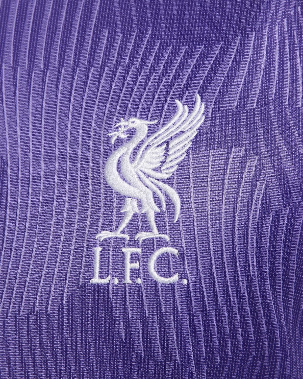 Close-up of white Liverpool FC Liverbird emblem embroidered on purple striped fabric (jersey)
