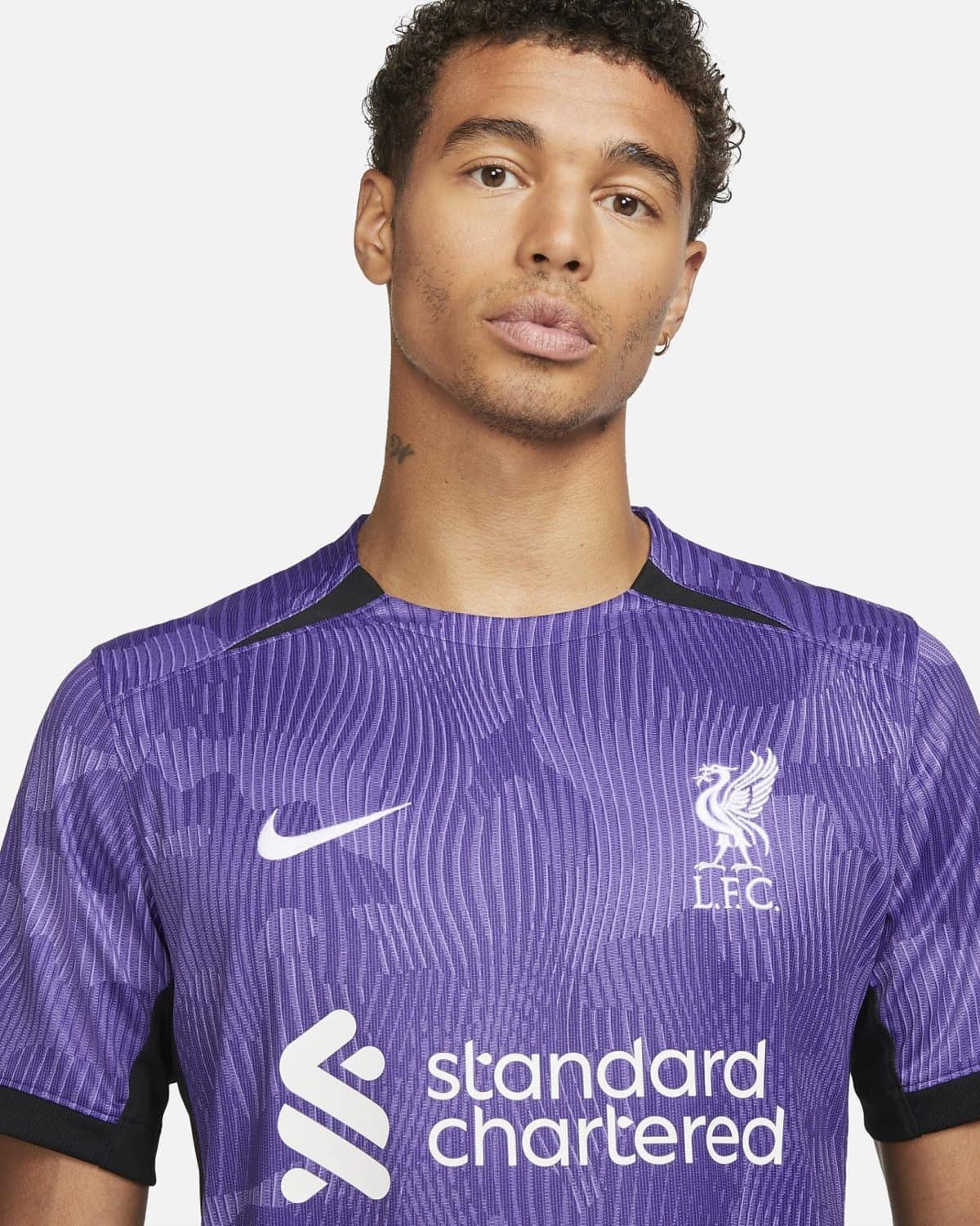 Close-up of a person wearing a purple Liverpool FC training jersey with the Standard Chartered logo on the chest