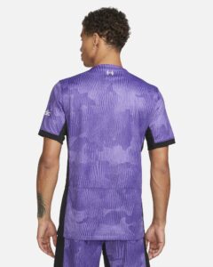 liverpool-third-jersey-202324-339931_b332c077-a55f-4568-865a-6984bc45b2f9 | UAE SPORT STORE Back view of a person wearing a purple camo-pattern athletic jersey with black side panels, short sleeves, and a small logo at the neck.