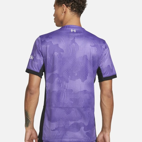 Back view of a person wearing a purple camo-pattern athletic jersey with black side panels, short sleeves, and a small logo at the neck.