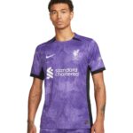 Young man wearing a purple Liverpool FC jersey with Standard Chartered sponsor logo front and crest on chest.