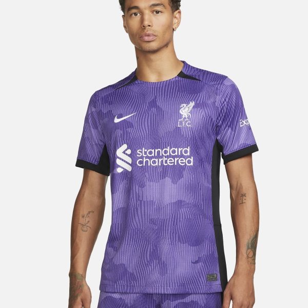 Male model wearing a purple Liverpool FC away jersey with Standard Chartered logo, facing forward against a light backdrop.