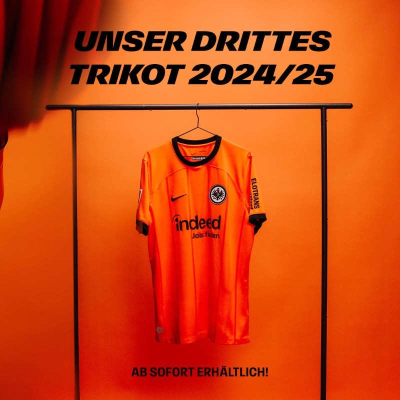 lixq8d9CMx9DLo9 | UAE SPORT STORE Orange football jersey hanging on a rack against an orange wall, with bold German text about the 2024/25 third kit and availability at the bottom.
