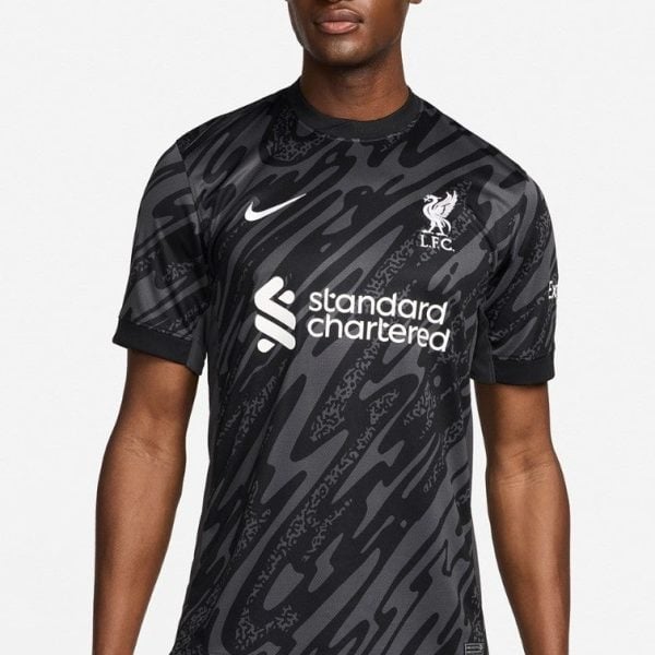 Male model wearing a black camouflage Liverpool FC away jersey with Nike swoosh and Standard Chartered sponsor.