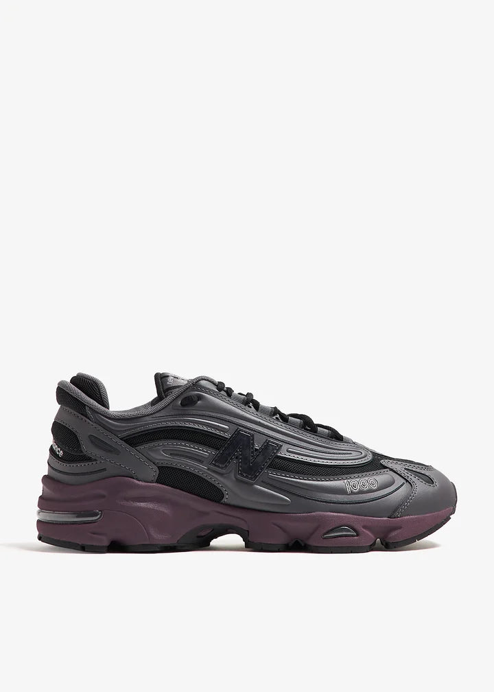 m1000eb-052_1 | UAE SPORT STORE Dark gray/black chunky athletic sneaker with a purple-maroon sole on a white background, side view emphasizing layered panels.