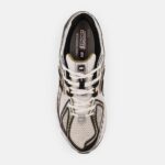 Top-down view of a beige and black athletic sneaker with white laces and an NB logo on the tongue area