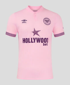Pink football jersey with crest on left chest, Umbro logo on right, star graphic and 'HOLLYWOODbet' sponsor across the front; striped sleeve cuffs.