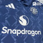 Close-up of a blue Manchester United jersey showing the Snapdragon sponsor logo and the club crest.