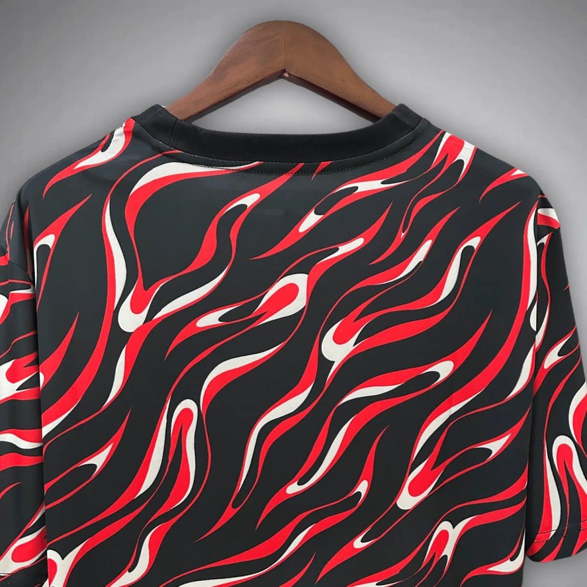 Black short-sleeve shirt on a wooden hanger with red and white flame pattern across the fabric.