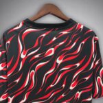 Black short-sleeve shirt on a wooden hanger with red and white flame pattern across the fabric.