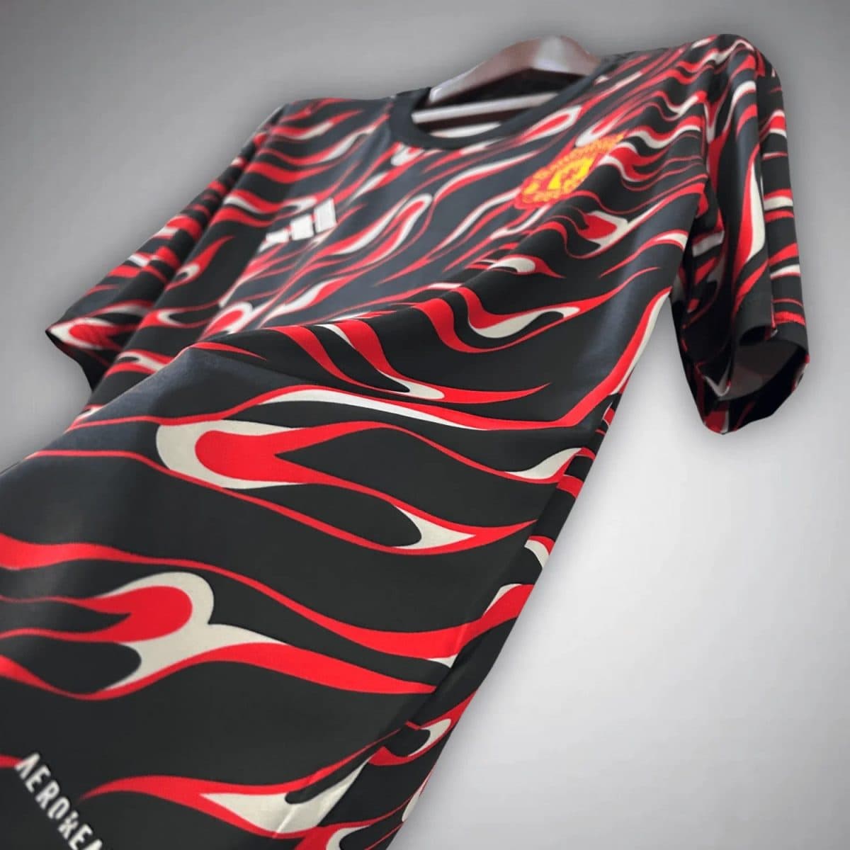 Black jersey with a red and white flame pattern on a hanger; Adidas logo visible on the chest area.