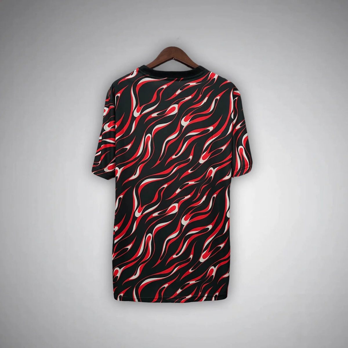 Black dress with a red and white flame pattern hanging on a wooden hanger against a gray background.