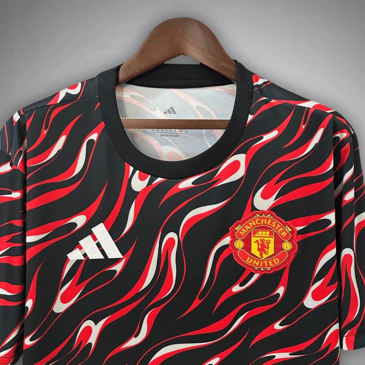 Manchester United football jersey with a black and red flame pattern, Adidas logo, and club crest on the chest.