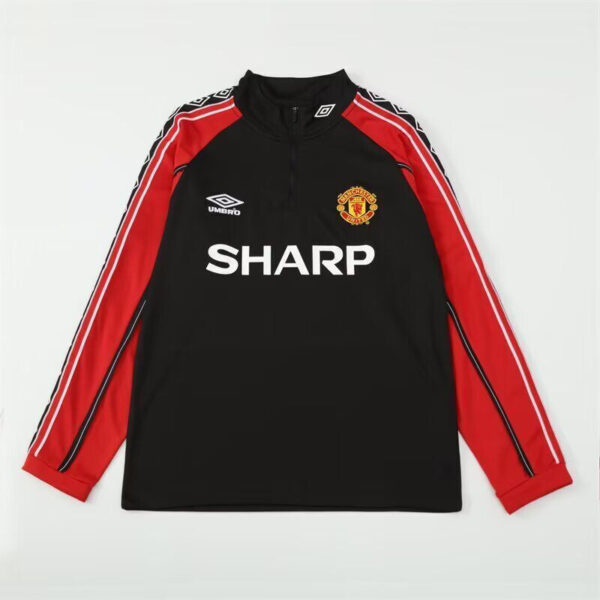 Manchester United training jersey: black body with red sleeves, SHARP sponsor, Umbro logo and club crest on chest