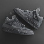 Pair of dark gray sneakers on a black background, showing mesh panels and visible air soles.