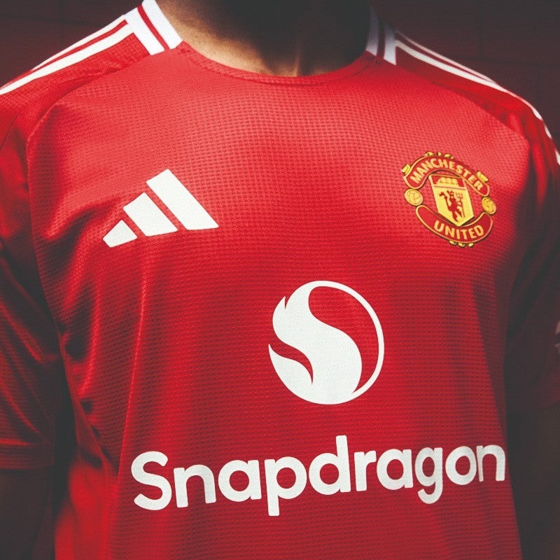 mcSXrTG7rbcToQu | UAE SPORT STORE Red Manchester United football jersey with Snapdragon sponsor logo on chest, Adidas-style white stripes on shoulders.