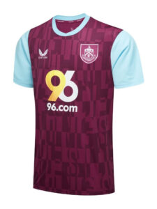 Maroon soccer jersey with light blue sleeves, crest on the chest, and a bold yellow '96.com' sponsor logo across the front.