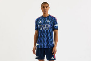 Male model wearing a blue zigzag-pattern football jersey with Emirates Fly Better sponsor.