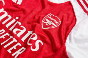 Close-up of a red Arsenal football jersey showing the club crest and Emirates sponsor lettering.