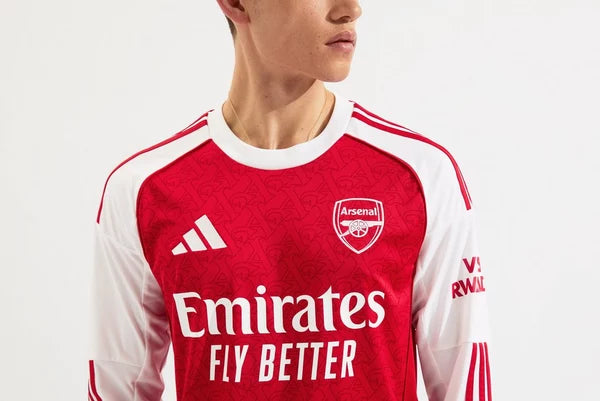 mji9536_d | UAE SPORT STORE Close-up of a person wearing an Arsenal football jersey: red shirt with Emirates Fly Better sponsor, Adidas logo, and club crest on white sleeves.