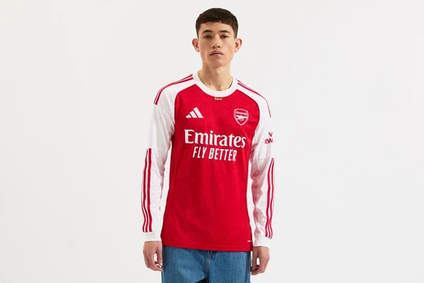 mji9536_f_1 | UAE SPORT STORE Man wearing a red Arsenal football jersey with white sleeves, standing against a plain white background; sponsor text reads 'Emirates FLY BETTER'.