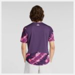 Back view of a person wearing a purple athletic jersey with pink abstract pattern on the sleeves and hem, gray background.