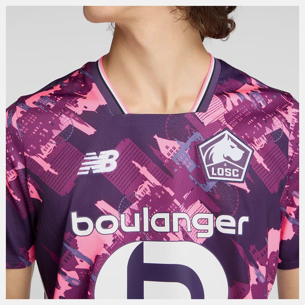 Back view of a person wearing a purple-pink LOSC football jersey with a cityscape pattern and a large number on the front.