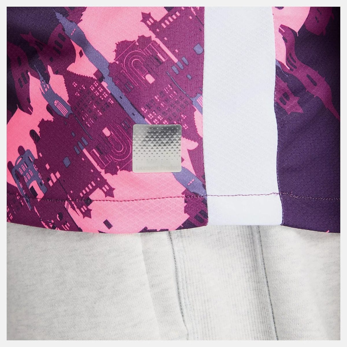 Close-up of a pink–purple patterned quilt with a small silver square patch.