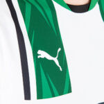 Close-up of a white Puma logo on a green panel of a sports jersey, with white and black trim visible.