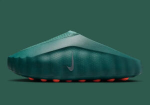 Dark green Nike soccer cleat with a perforated texture and orange studs on a matching green background