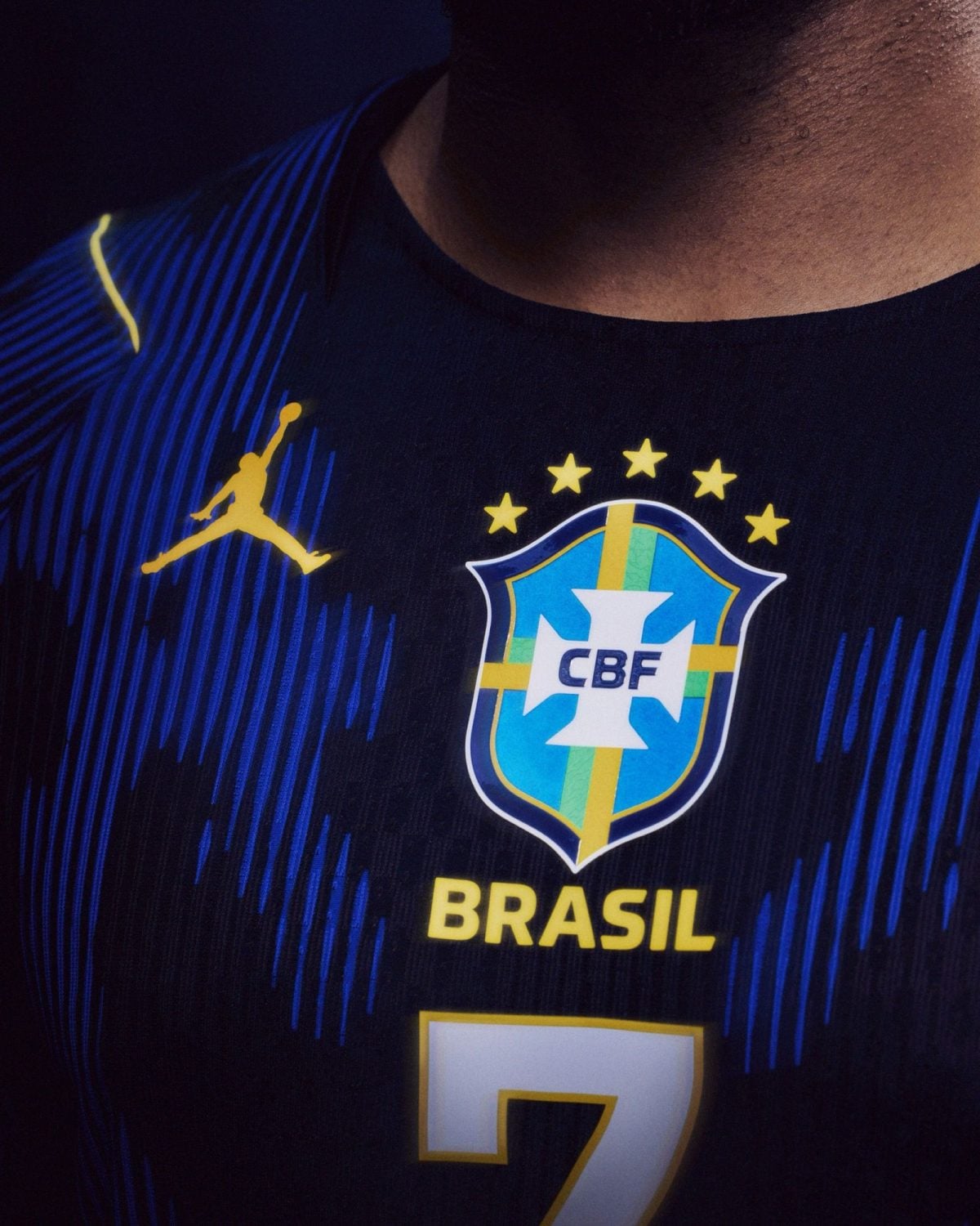 Close-up of a Brazil national team jersey: crest, blue fabric with stripes, and the number 7 on the front