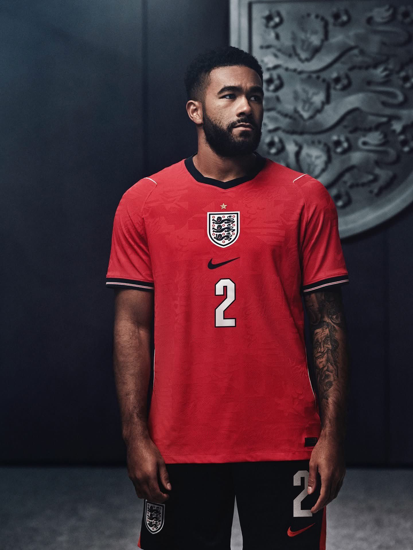 nss-maglie-mondiale-2026-inghilterra-2 | UAE SPORT STORE Male footballer in a red England jersey with number 2, standing against a dark backdrop.