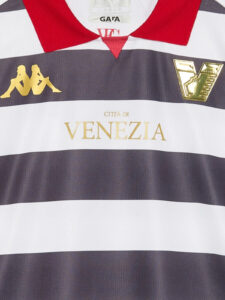 Close-up of a striped rugby/football jersey with purple and white horizontal bands, red collar, gold 'CITÀ DI VENEZIA' text, and logos on the chest.