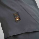 Close-up of dark textured fabric with a small gold badge showing a leaping Puma and the words 'Authentic Licensed Football'