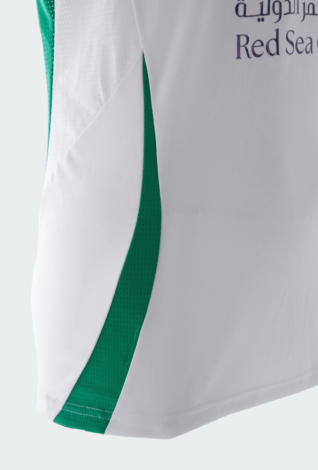oSfSYNM0fX0igjf | UAE SPORT STORE Close-up of a white sports jersey with a green side stripe and partial 'Red Sea' text.