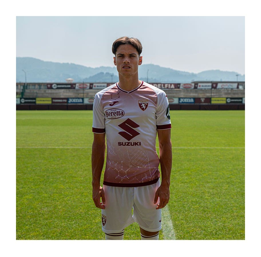 ocAMHnw4tg1DUur | UAE SPORT STORE Soccer player in pink-white kit with Suzuki and Beretta logos, standing on a sunlit grass field.