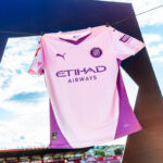 Pink soccer jersey with Etihad Airways sponsor hanging on a clothesline outdoors.